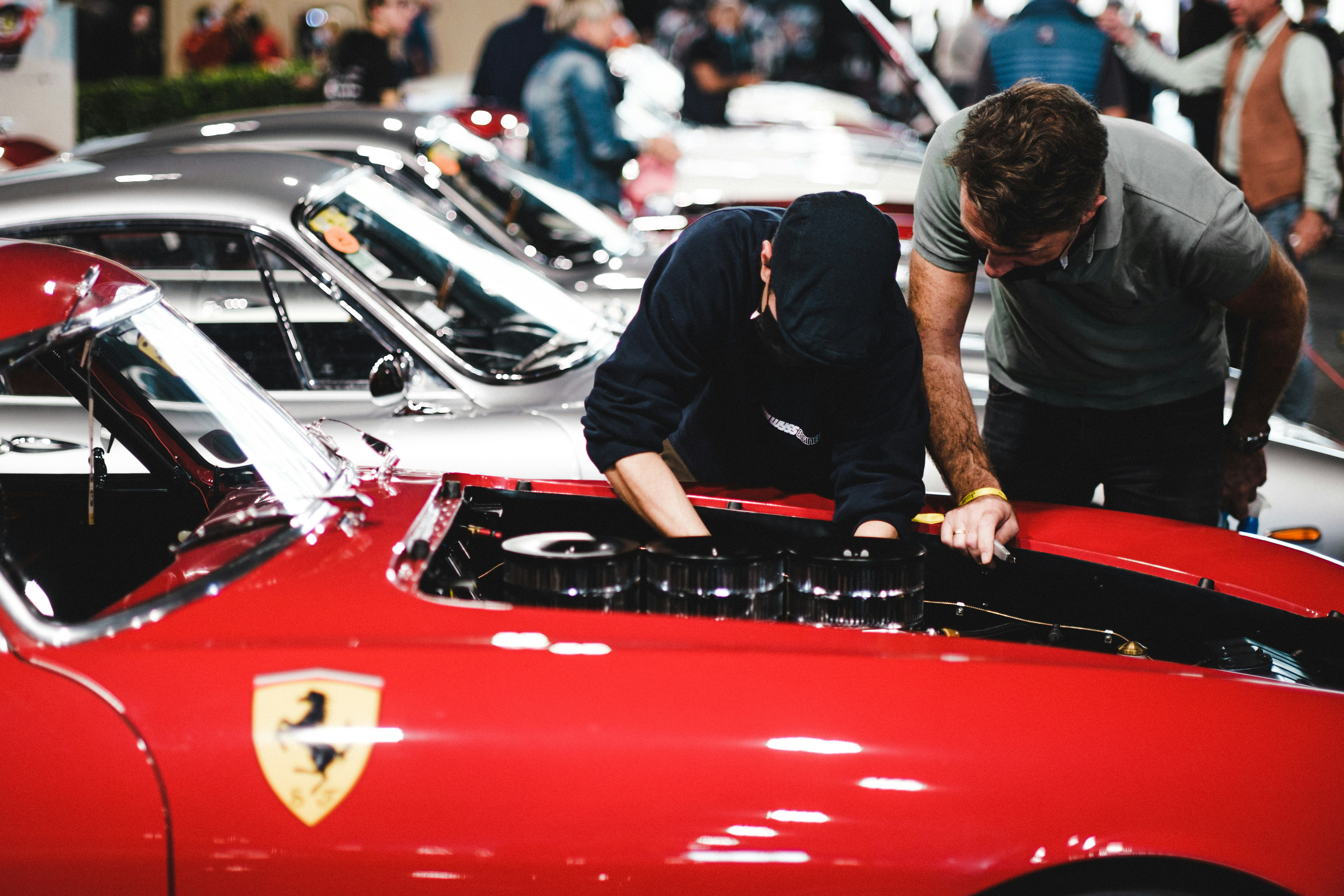 man in black t-shirt and black pants leaning on red car